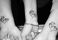 two girls with matching tattoos on their arms holding each other's hands in the shape of hearts