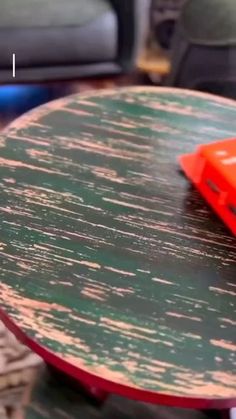 an orange toy car sitting on top of a wooden table next to a green chair