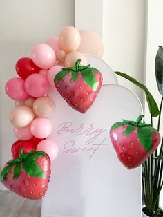 some balloons are attached to the back of a white chair with strawberries on it