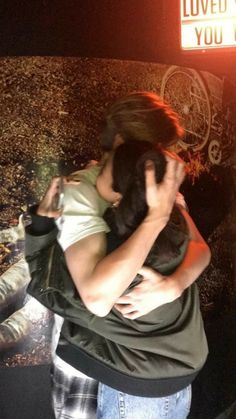 a woman holding a small dog in her arms while standing next to a sign that says loved you