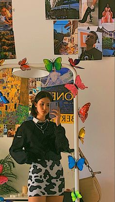 a woman taking a selfie in front of a mirror with butterflies all over it