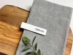 a wooden cutting board topped with a piece of cloth next to a plant on top of it