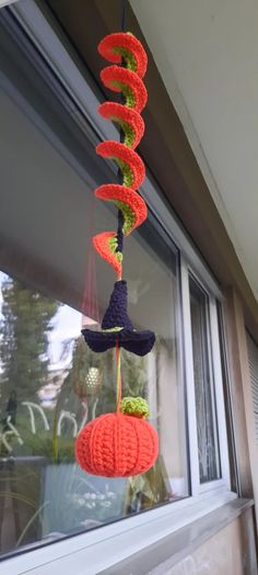 a crocheted wind chime hanging from the side of a window sill