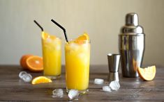 two glasses filled with orange juice sitting on top of a wooden table