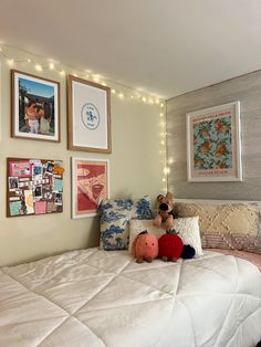 a bedroom with pictures on the wall above the bed and stuffed animals on the pillow