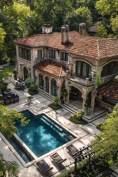 an aerial view of a large house with a pool in the middle and trees surrounding it