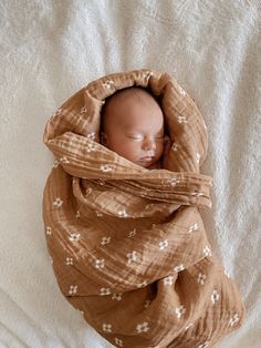 a baby wrapped in a blanket on top of a bed