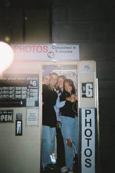 three women standing in front of a vending machine with their arms around each other