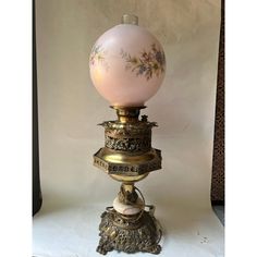 an old fashioned lamp with a pink glass ball on it's top and gold trimmings