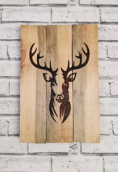 a wooden sign with a deer's head drawn on it, mounted to the side of a brick wall