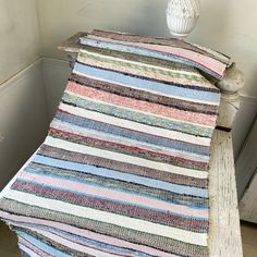 a white vase sitting on top of a table next to a pile of rugs