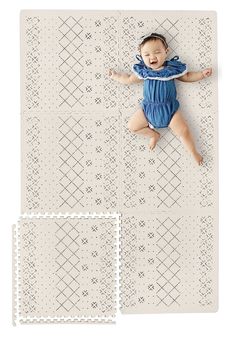 a baby laying on top of a mat next to two pieces of cut out paper