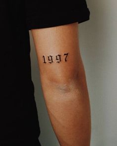 a person with a small tattoo on their arm that reads,'1971'in cursive font