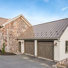 two garages in front of a brick building with metal roofing on the side