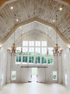 a large open room with chandeliers and windows in the ceiling is decorated with wood planks