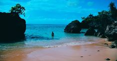 a person standing in the ocean near some rocks