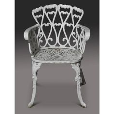 an old white chair with ornate carvings on the back and arms, sitting against a gray background