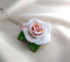 a white rose with green leaves attached to a chain