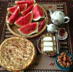 watermelon and almonds are on the table next to a bowl of tea