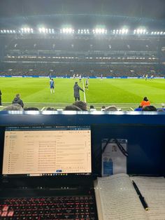 an open laptop computer sitting on top of a desk in front of a soccer field