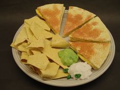 a plate with chips, guacamole and tortilla wedges on it