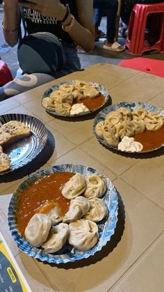 three plates with dumplings on them sitting on a table