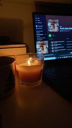 a candle sitting in front of a laptop computer