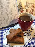 a cup of coffee and some cookies on a plate with a book in the background