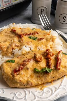 two pieces of chicken with rice and sauce on a plate