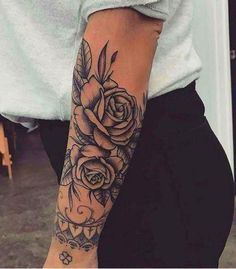 a woman's arm with roses and leaves tattooed on the side of her arm