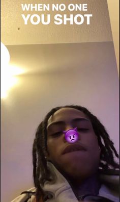 a young man with dreadlocks and a purple light in his eye looks up at the ceiling