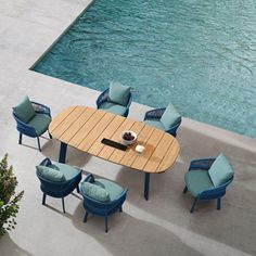 an outdoor dining table with blue chairs next to a pool