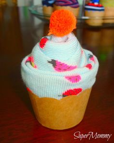 a knitted cupcake with an orange pom - pom sits on a table