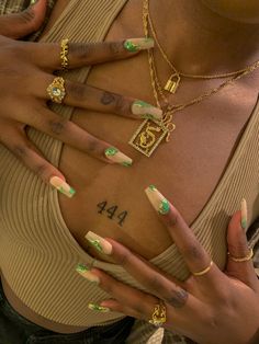 a woman with green and white nail polish holding her hands in front of her chest