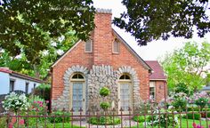 a brick house with flowers in front of it and a fence around the yard area