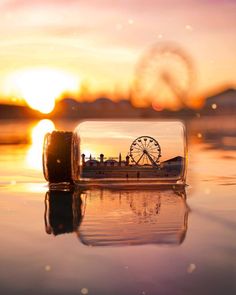 a bottle with a spinning wheel in it sitting on the beach