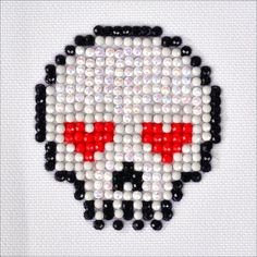 a cross stitch skull with red eyes on it's face is shown in black and white