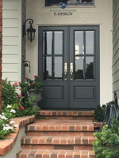 the front door of a building with flowers and potted plants on the steps leading up to it