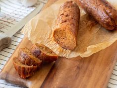 two sausages sitting on top of a wooden cutting board