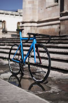 a blue bike parked on the side of a building next to steps and water puddles