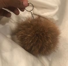 a person is holding a furry ball keychain