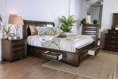 a bed sitting on top of a wooden floor next to a dresser with drawers under it