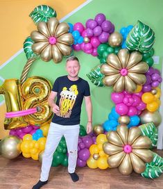 a man standing in front of a large balloon arch with the number twenty eight on it