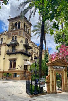 an ornate building with palm trees in the foreground and a gated entrance to it