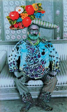 a man sitting on top of a white bench wearing a hat with flowers on it