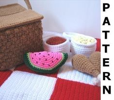 crocheted watermelon and other items are on a blanket next to a basket