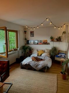 a bed sitting in a bedroom next to a window with potted plants on it