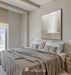 a large bed sitting in a bedroom next to a painting hanging on the side of a wall