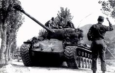 a man standing next to a tank on the road