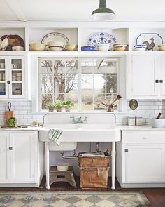 a kitchen filled with lots of white cabinets and counter top space next to a window